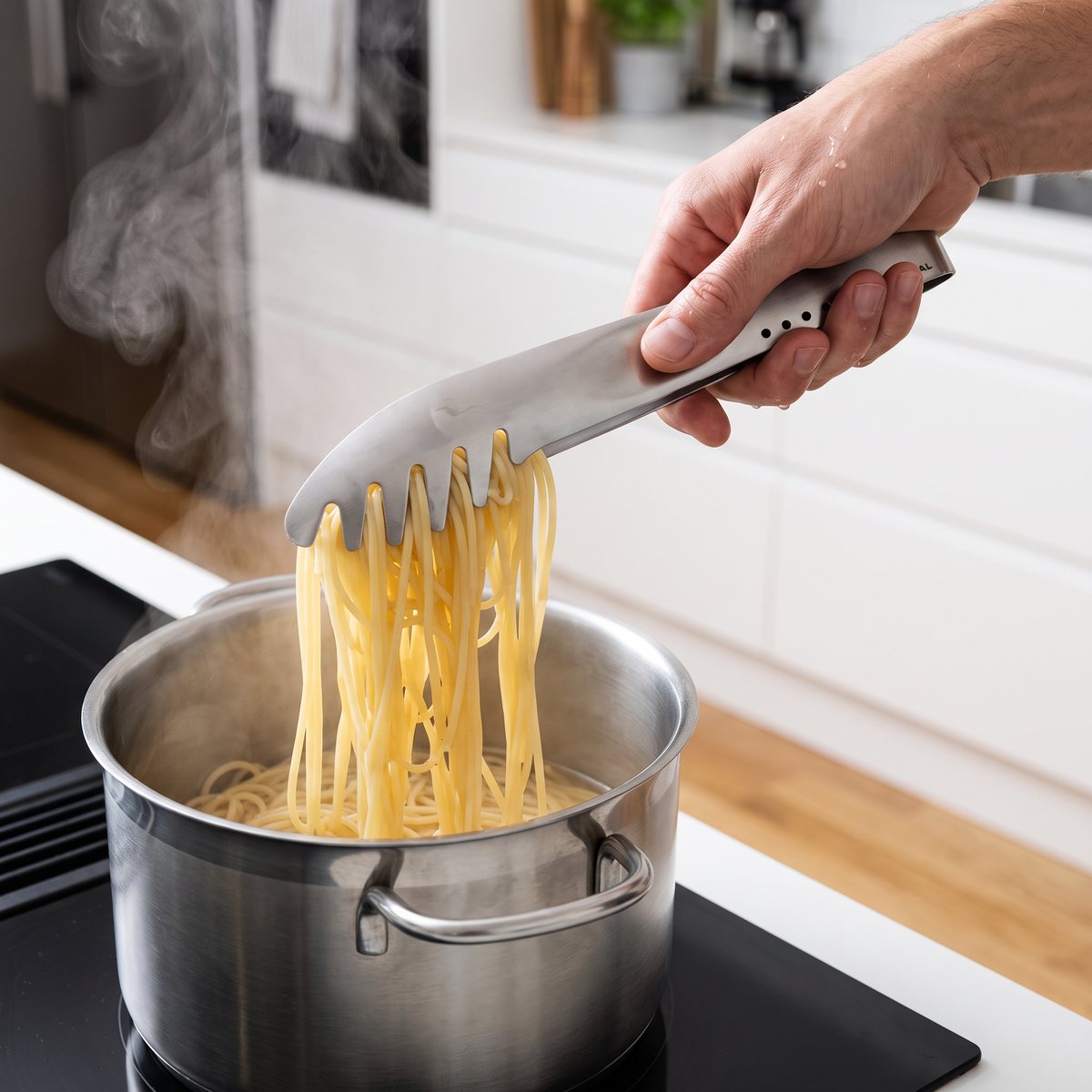 Global GS-67 pastatång lyfter nykokt spaghetti ur en kastrull på induktionshäll i ett svenskt kök