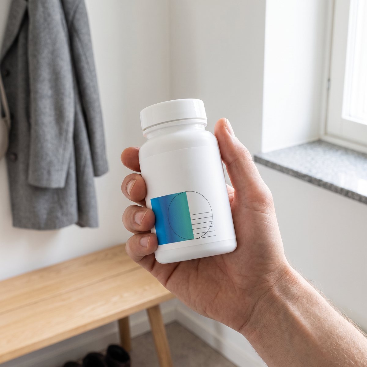 Hand som håller en vit flaska omega-3 i en ljus svensk hall