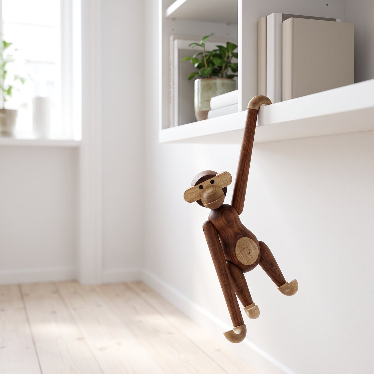 Kay Bojesen Apa Liten i teak och limba hänger i armarna från en vit vägghylla i ett ljust vardagsrum