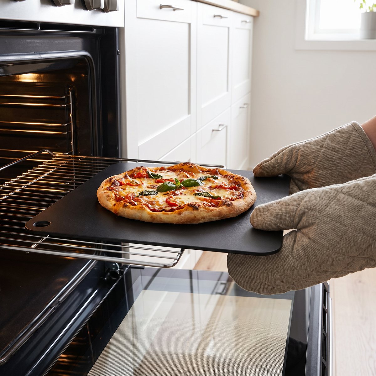 Svart kvadratiskt Dorre bakstål med pizza i en öppen ugn i ett svenskt kök