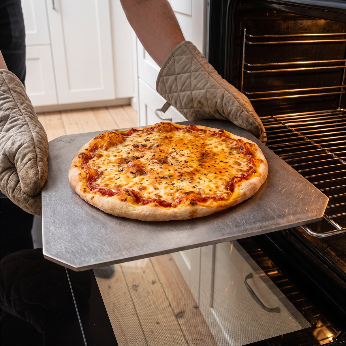 Gourmetstål Classic pizzastål med nygräddad pizza, burket ur en ugn i ett svenskt kök