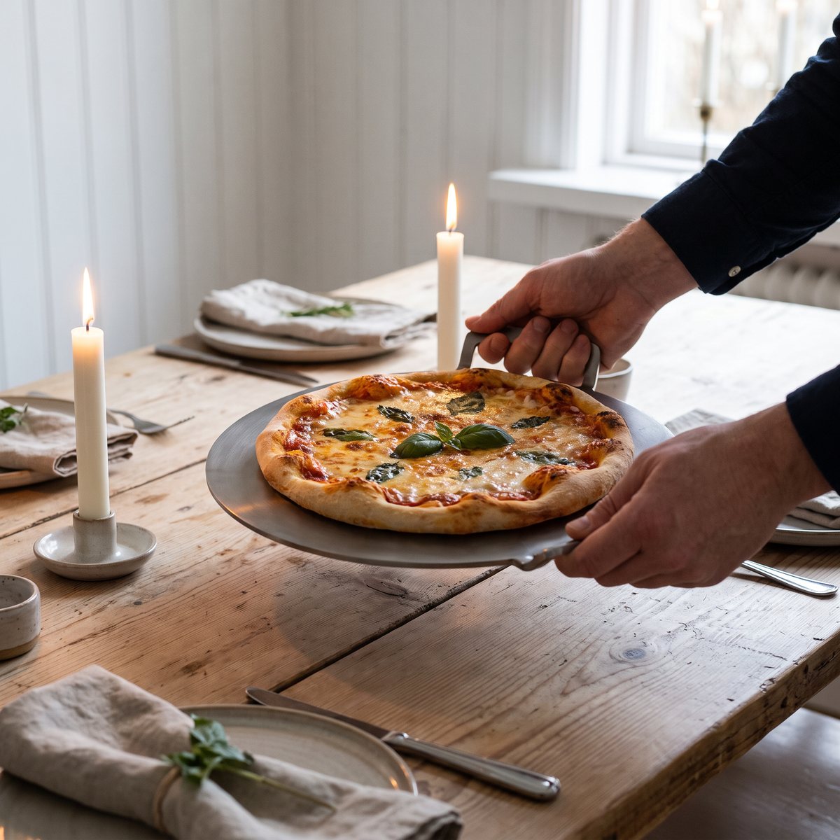 Runt Gourmetstål pizzastål med grepp som serverar pizza vid ett dukat middagsbord i ett svenskt hem