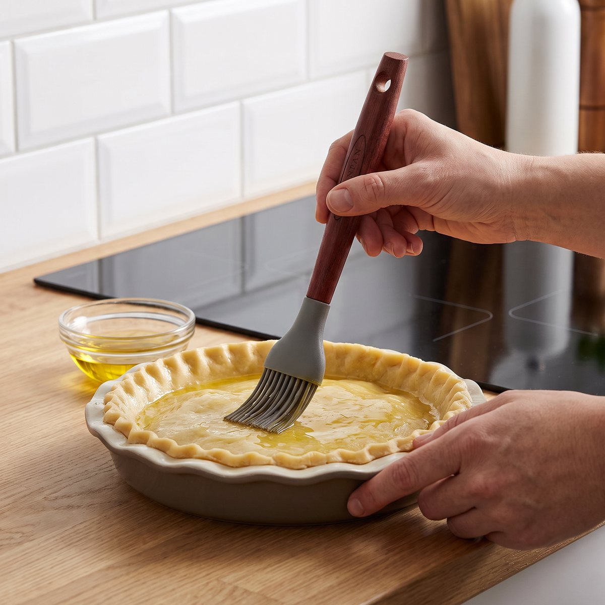 Scanpan bakpensel med trähandtag och silikonborste som penslar olja på en pajskal i ett svenskt kök