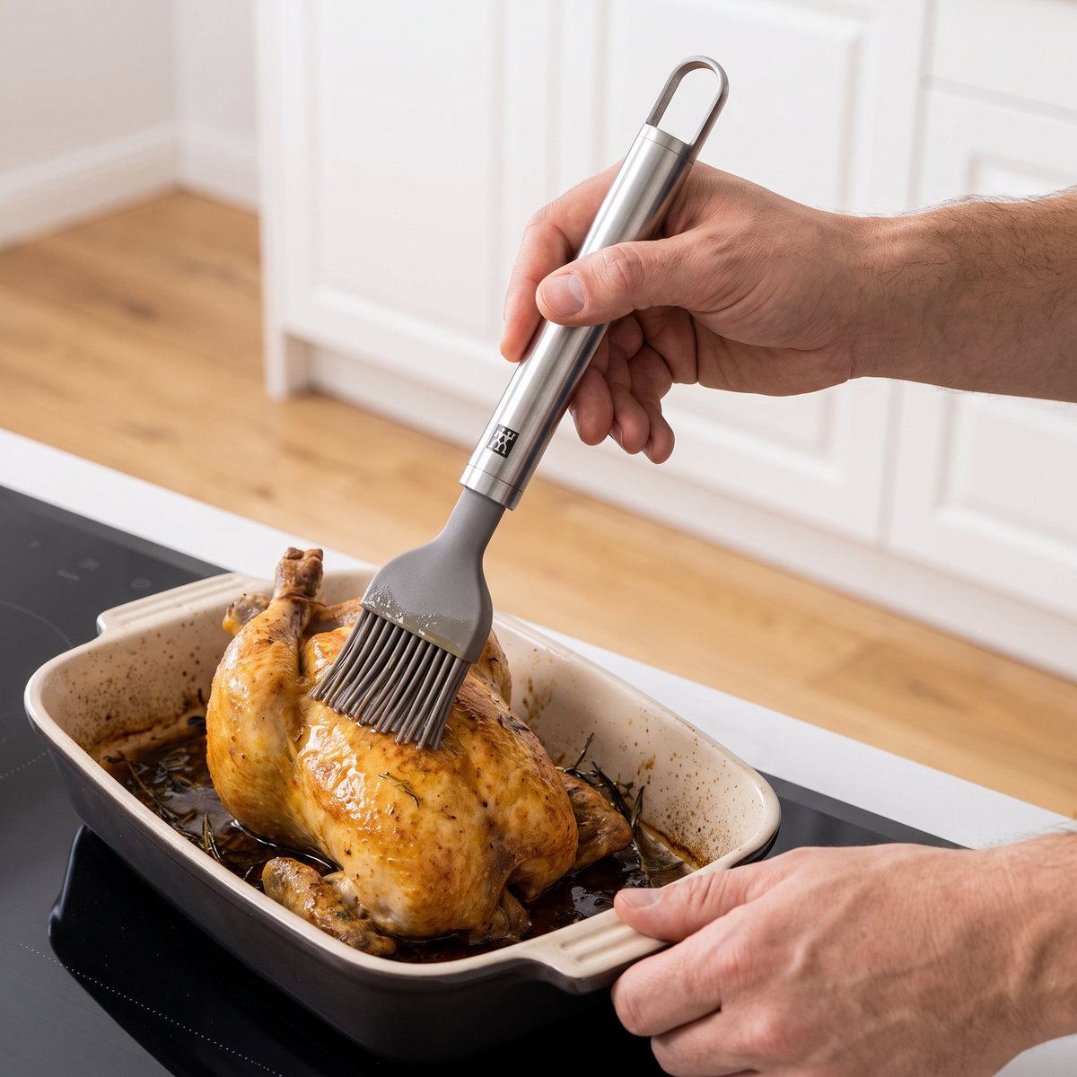 Zwilling Pro silikonpensel med långt rostfritt handtag som penslar en kyckling i långpanna vid en induktionshäll