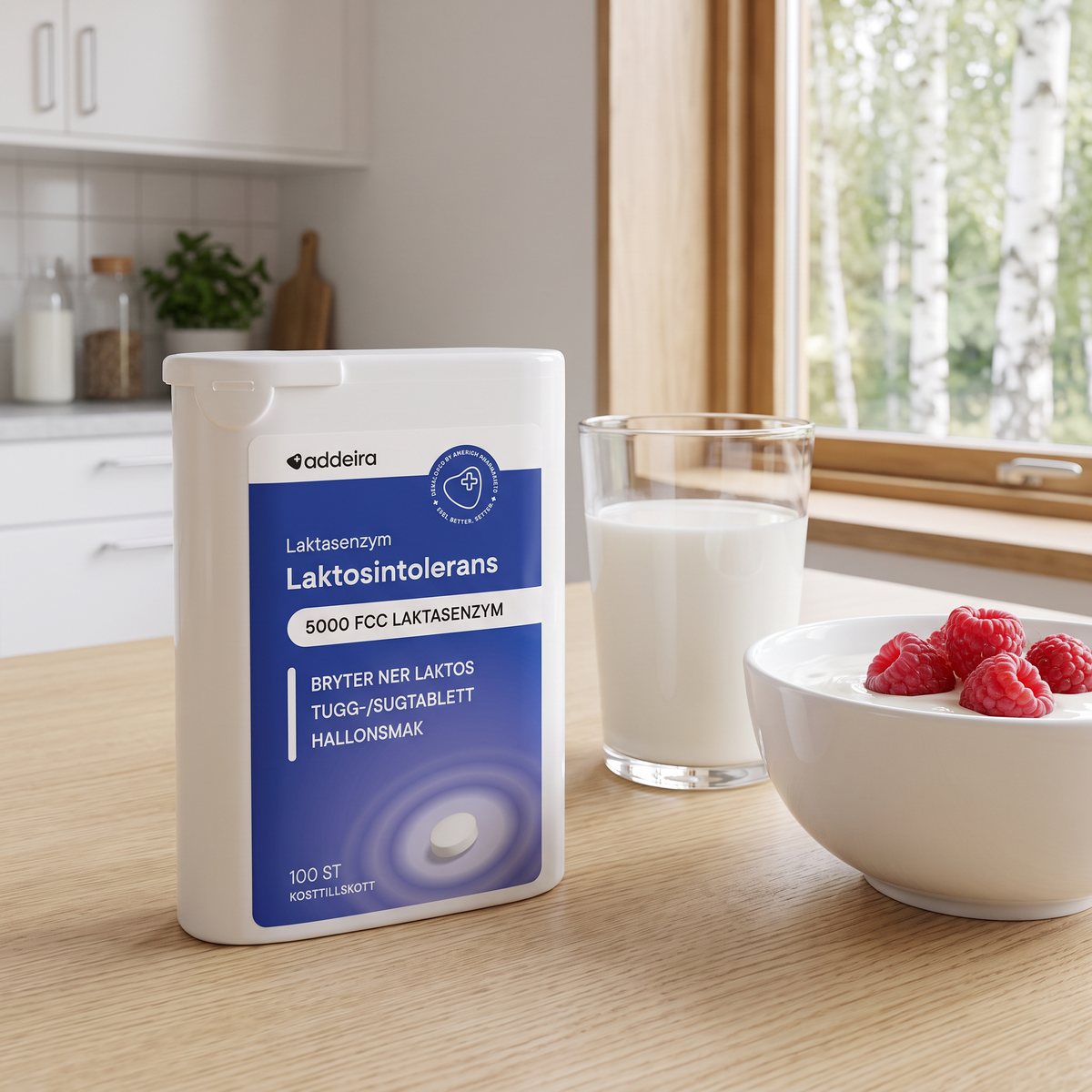 Tuggtabletterna Addeira Laktasenzym i en vit tablettdosa på ett frukostbord med mjölk, hallon och yoghurt i ett svenskt kök
