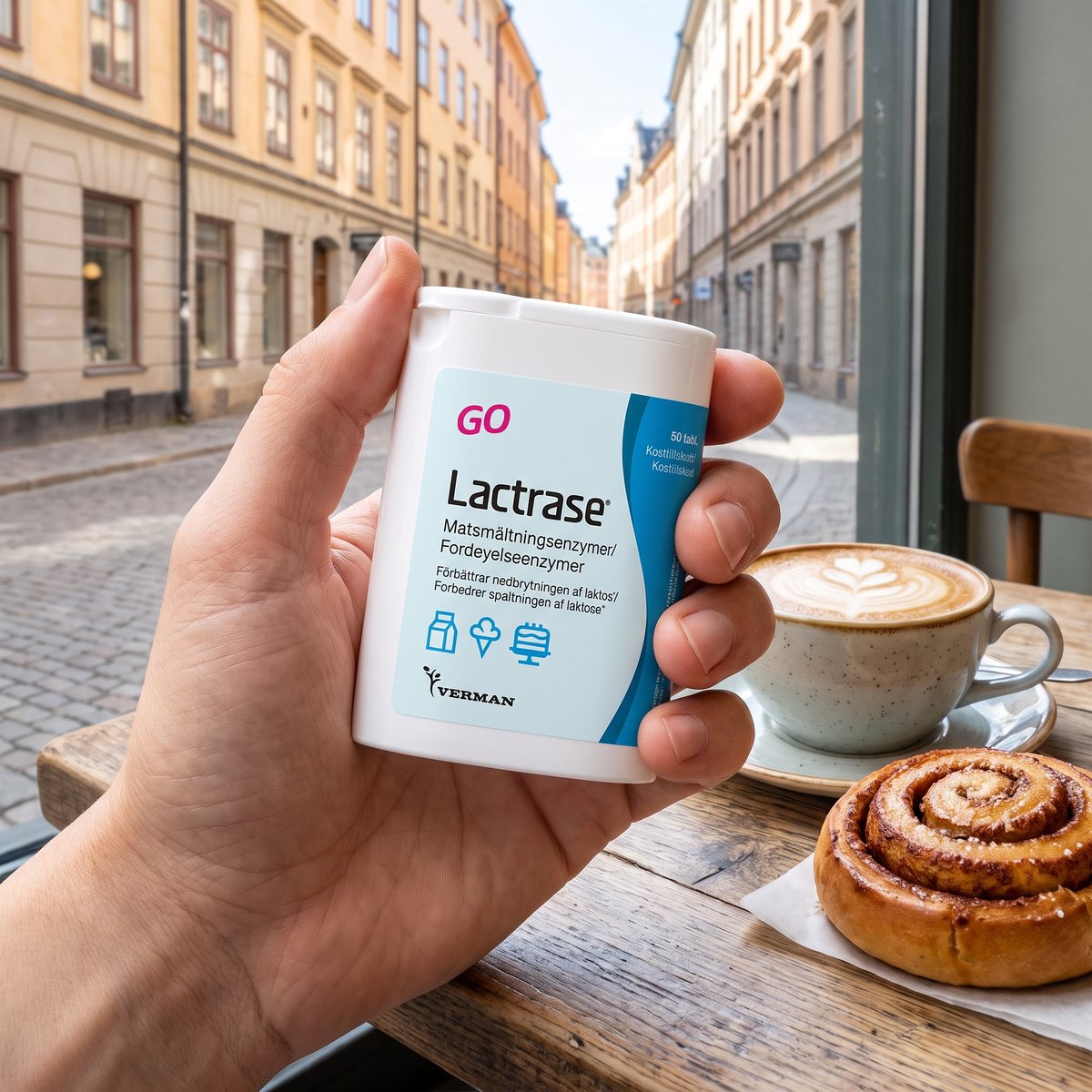 Hand som håller en dosa Lactrase Go över ett svenskt cafébord med cappuccino och kanelbulle