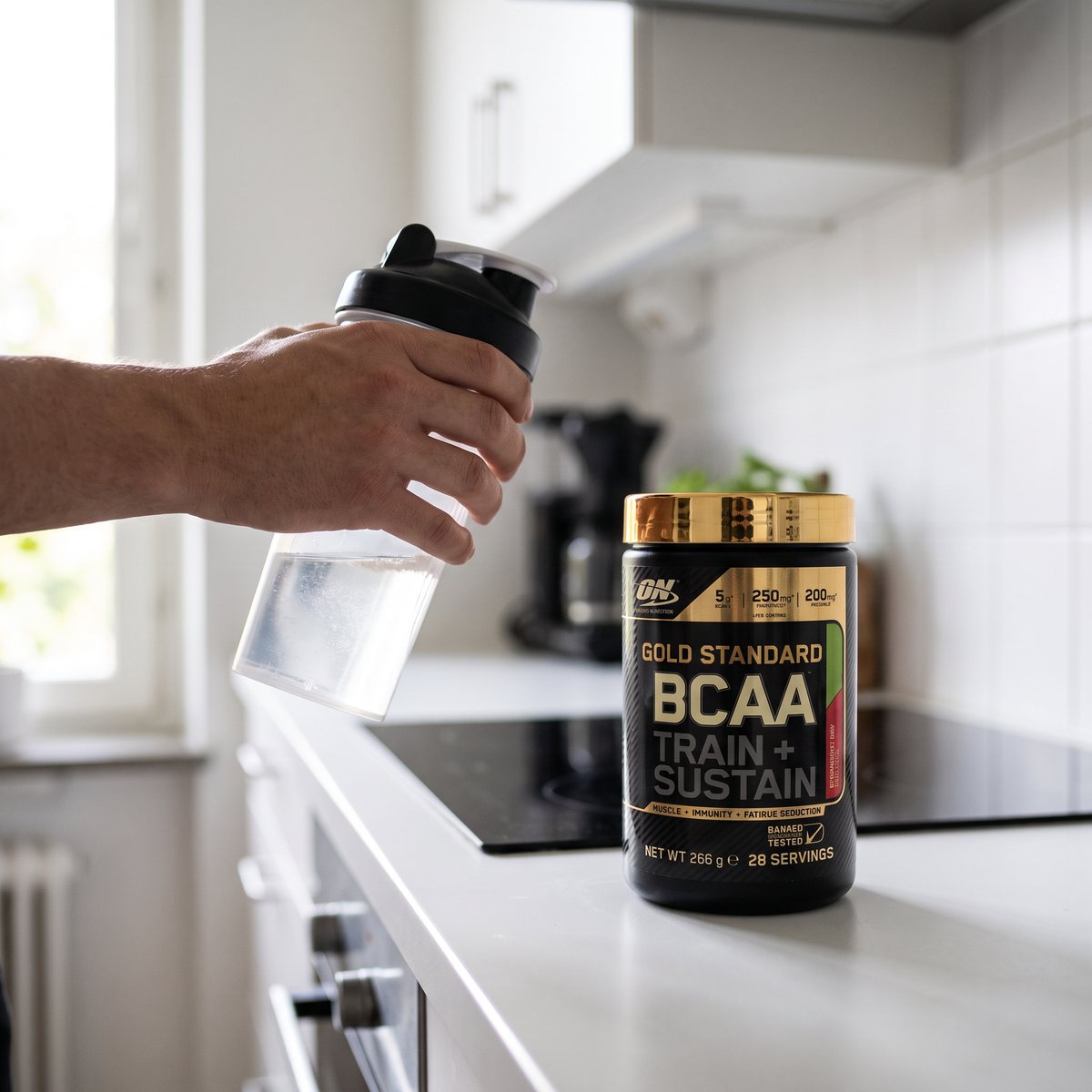 Burk med Optimum Nutrition Gold Standard BCAA på en vit bänkskiva i ett svenskt kök med induktionshäll och en shaker