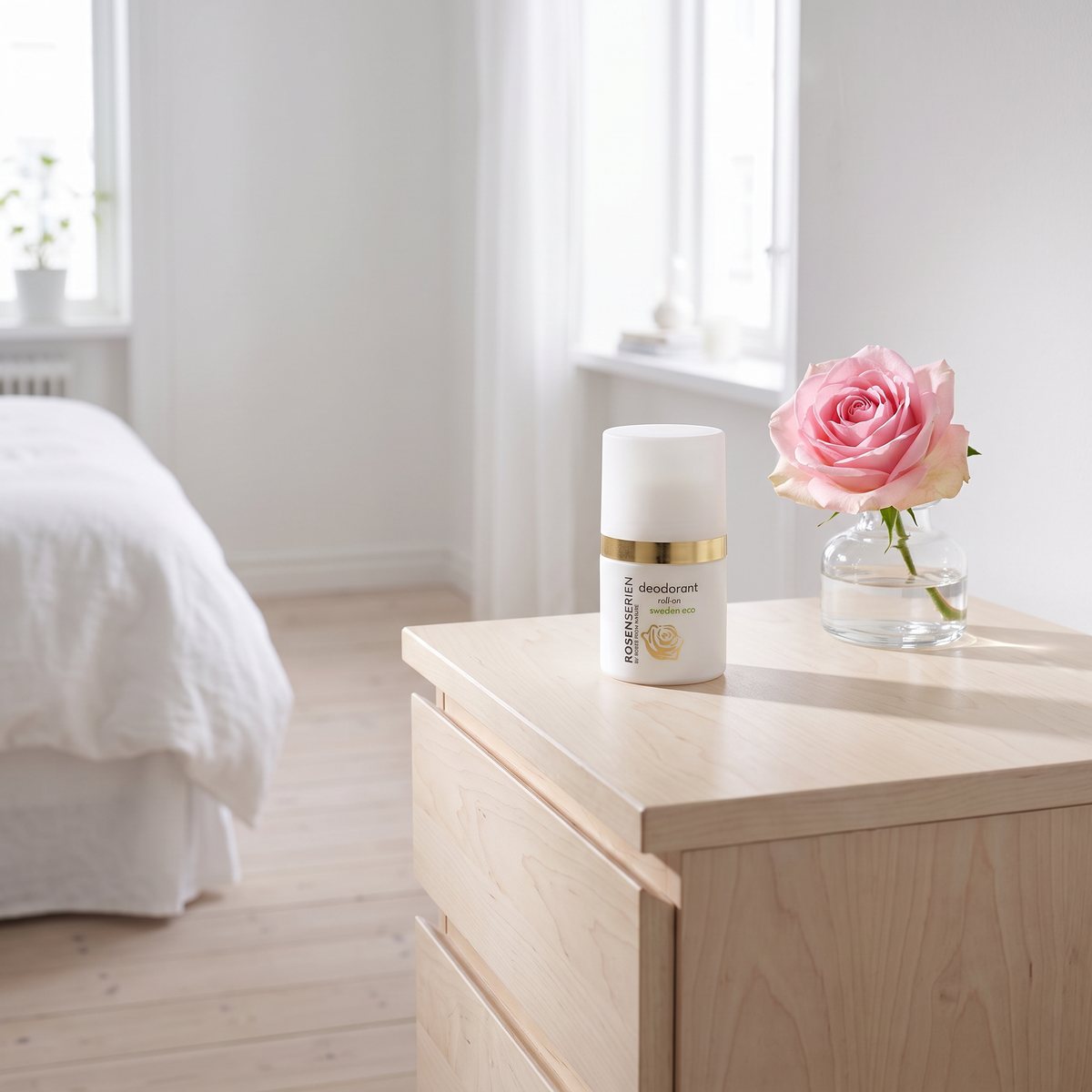 Rosenserien Deodorant Roll-on på en byrå av björk i ett svenskt sovrum bredvid en ros i vas