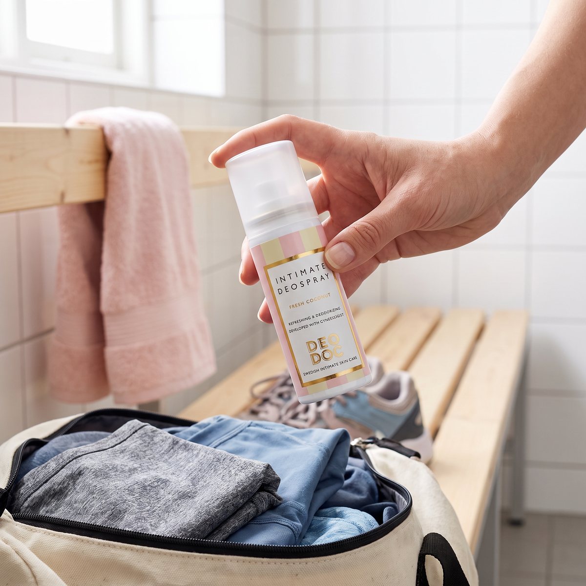 DeoDoc Fresh Coconut Intimate Deospray hålls i handen vid en gymväska i ett svenskt omklädningsrum