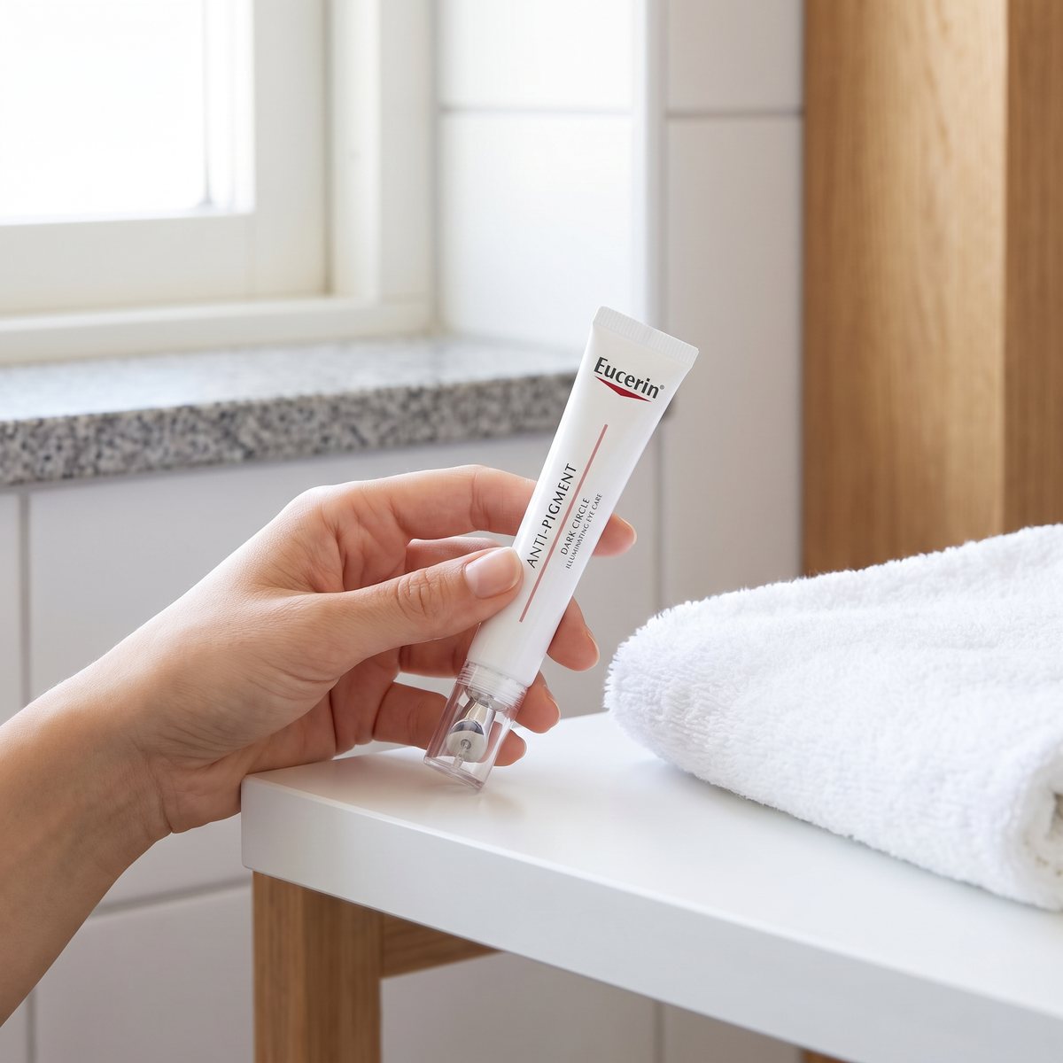 Eucerin Anti-Pigment Dark Circle-tuben med rullapplikator hållen i handen i ett svenskt badrum