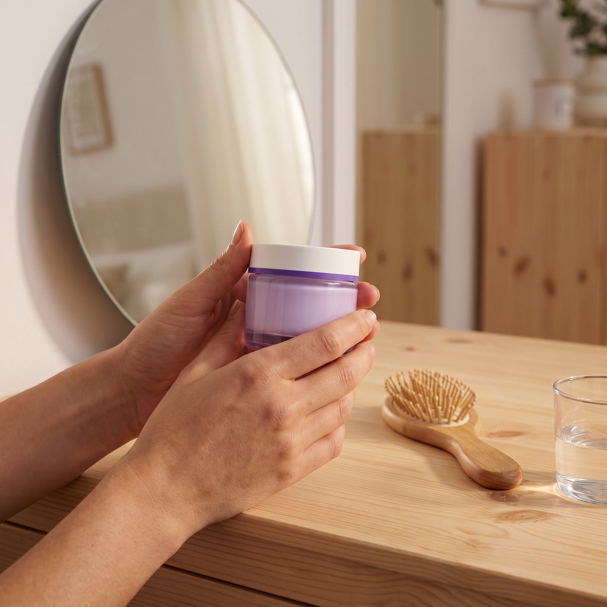 No7 Pure Retinol Night Repair Cream i händerna vid en sminkbord med rund spegel i ett svenskt sovrum