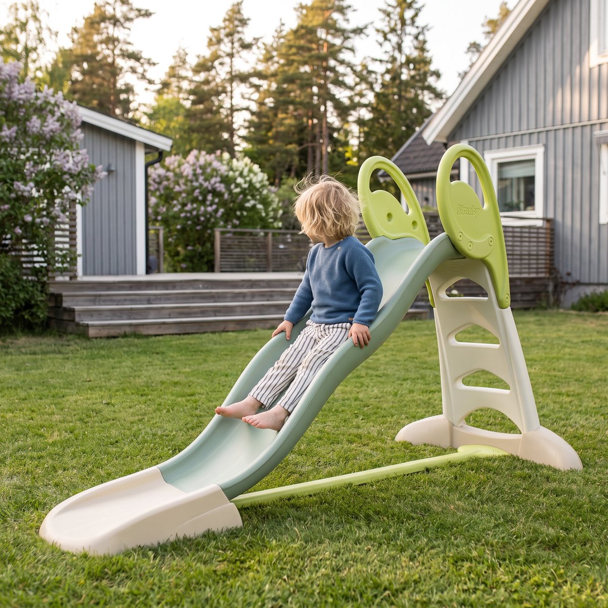 Smoby Life XL, en lång grön rutschkana på en gräsmatta i en svensk trädgård, med ett barn som åker ner