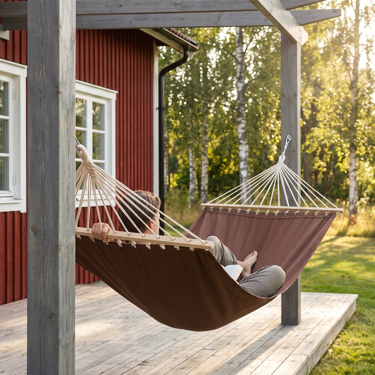 Brun vidaXL-hängmatta med trästänger och vita rep, upphängd i en pergola på altanen vid ett rött svenskt hus