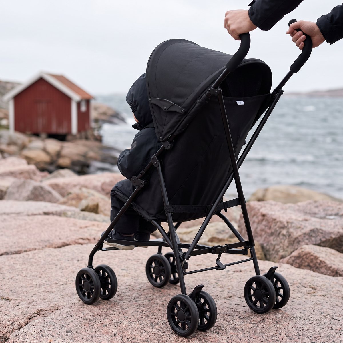 Svart Beemoo Move Flexi med sufflett på granithällar vid havet på den svenska västkusten