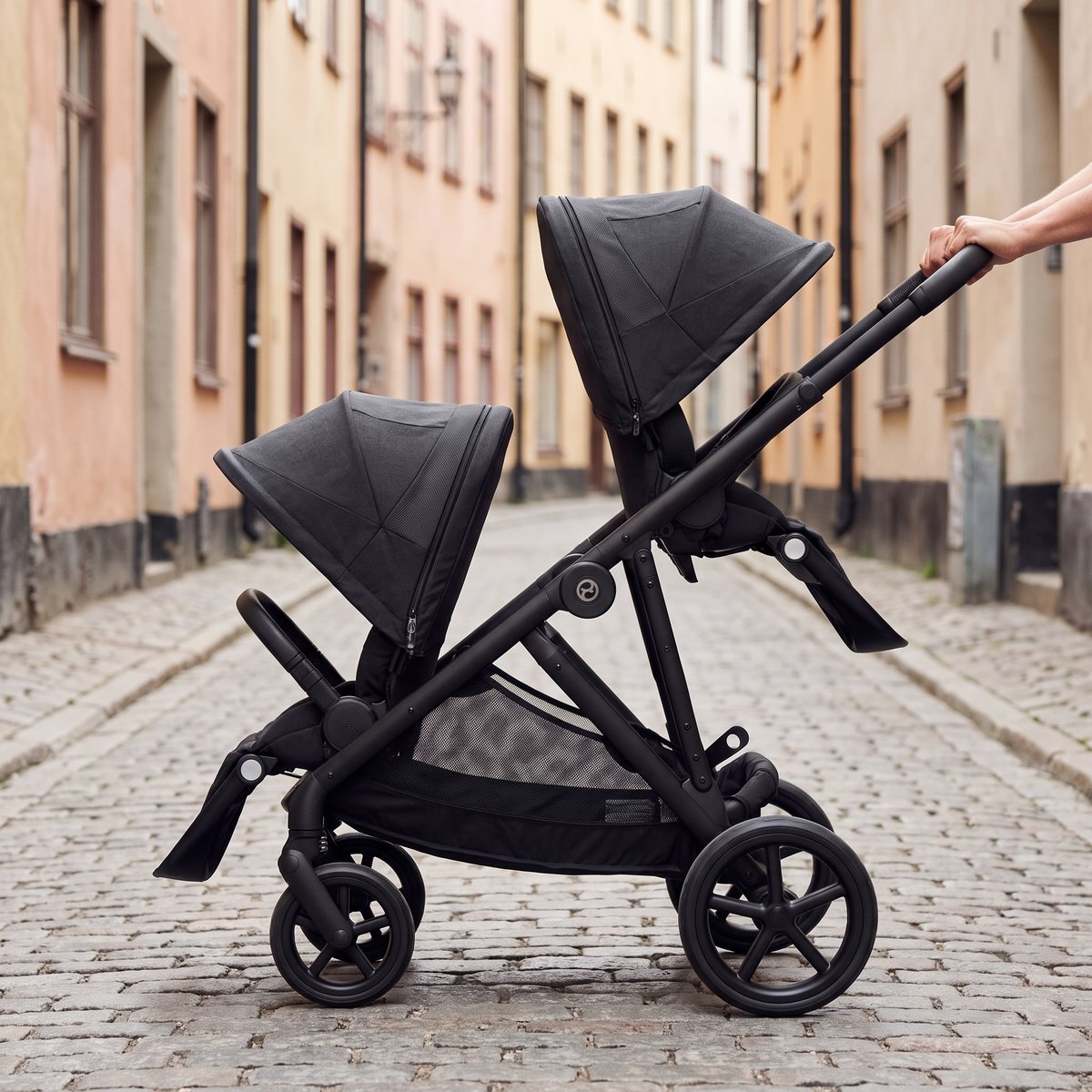 Cybex Gazelle S med två sittdelar efter varandra skjuts genom en smal kullerstensgränd i Gamla stan