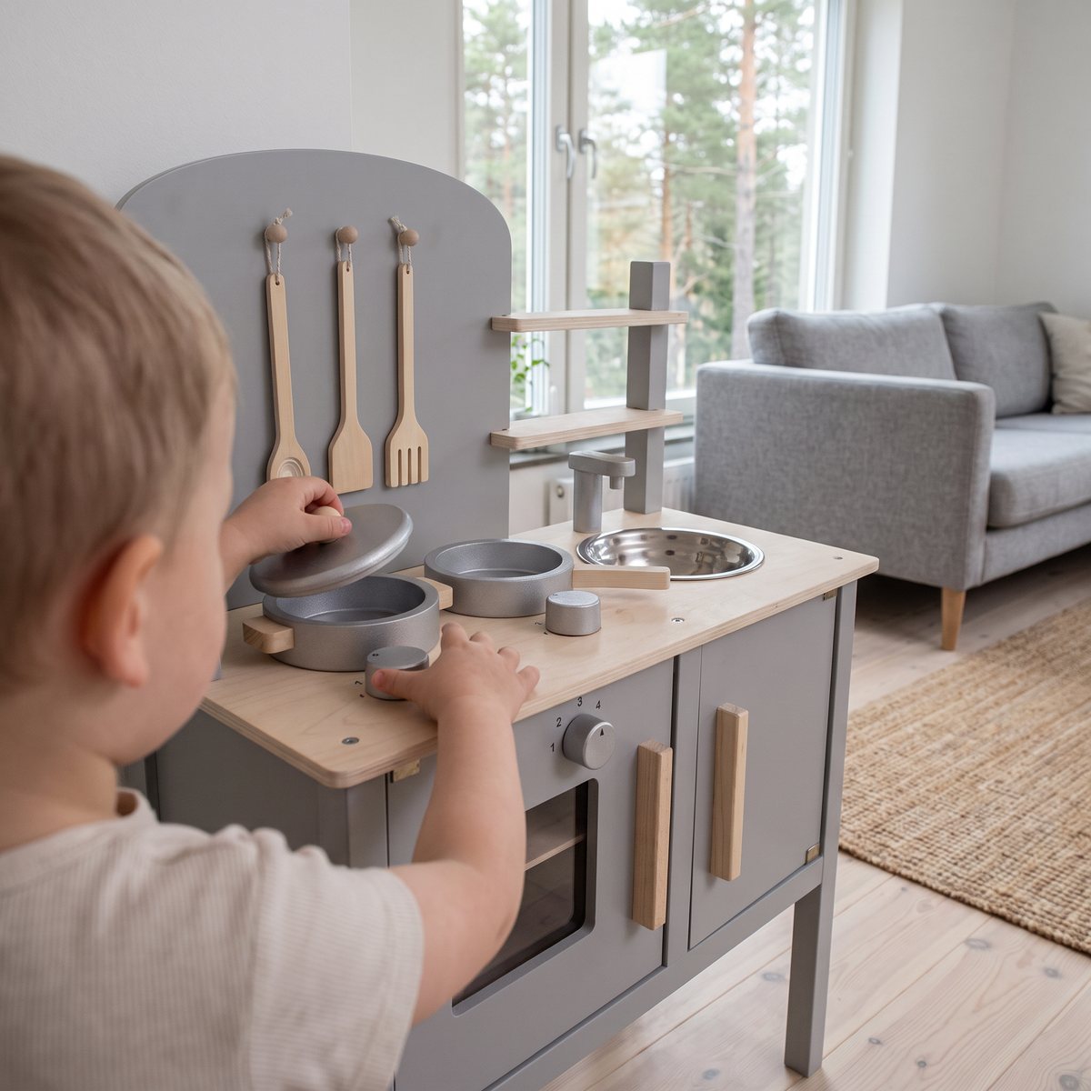 Jabadabado Leksakskök Grå i grått trä med kastrull, stekpanna och diskho i ett ljust svenskt vardagsrum med tallar utanför fönstret