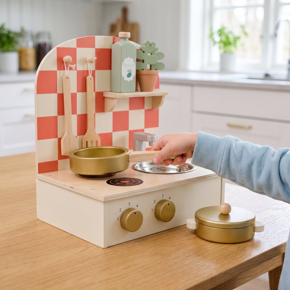 Jabadabado Leksakskök Litet Beige med rutigt bakstycke, guldfärgad stekpanna och kastrull på ett ljust köksbord i ett svenskt kök
