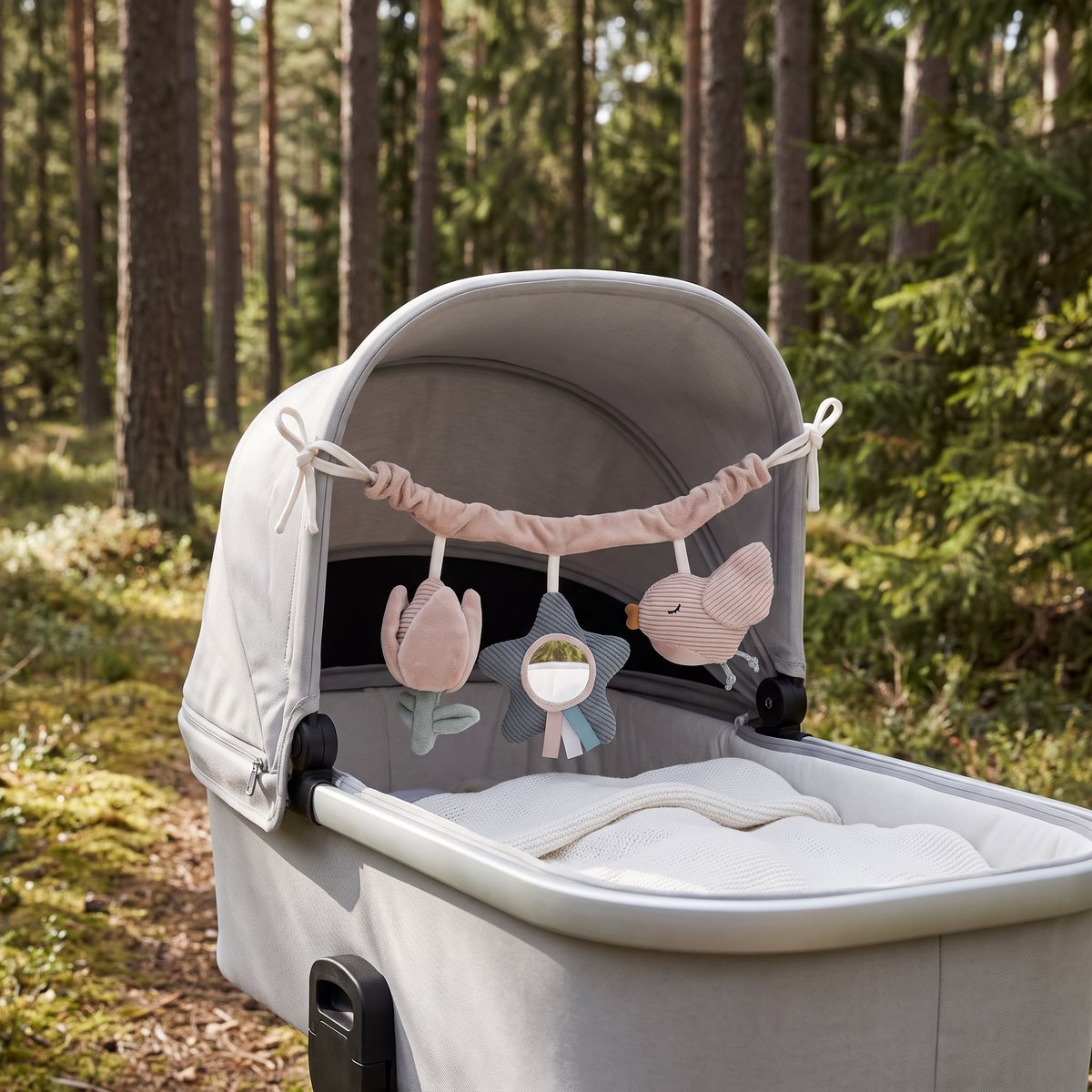 Jollein Lovely Birds-kedja spänd tvärs över en ljusgrå liggdel i en svensk tallskog