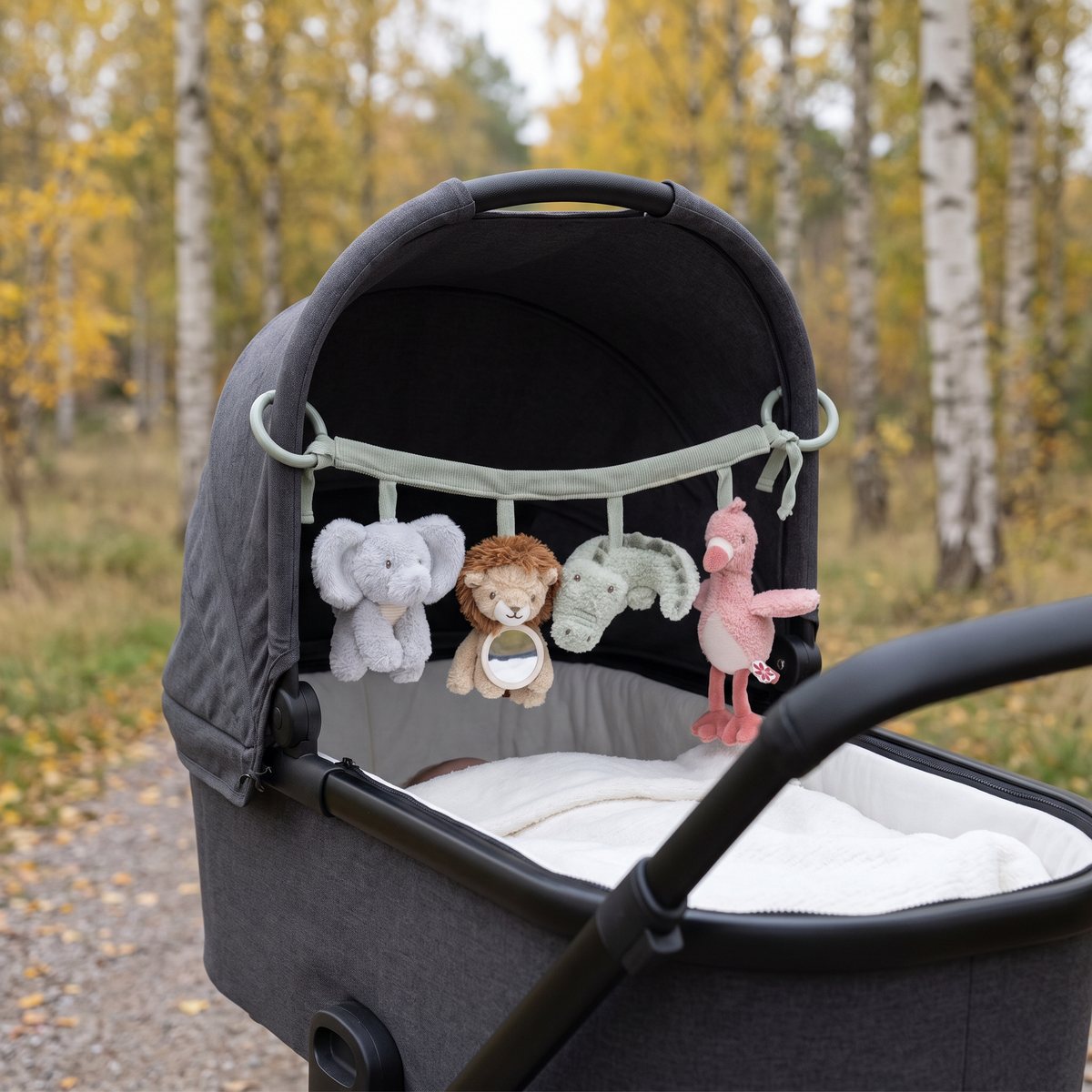 Little Dutch barnvagnshänge med elefant, lejon, krokodil och flamingo under suffletten på en grå barnvagn i en svensk björkskog på hösten