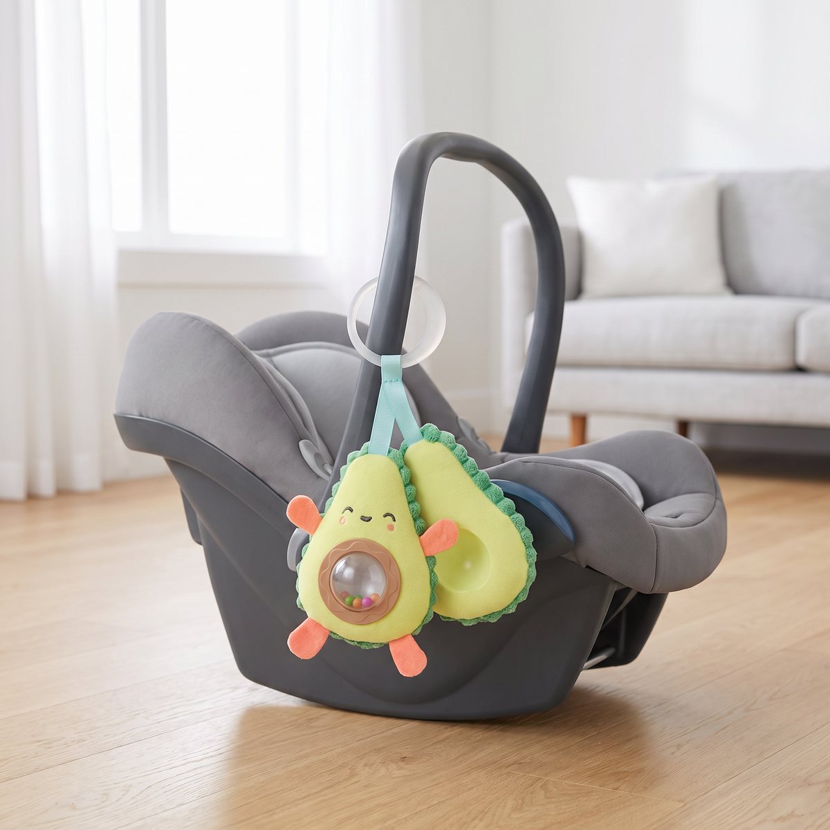Skip Hop-avokadon i plysch hängd på bygeln till ett grått babyskydd i ett ljust vardagsrum med trägolv
