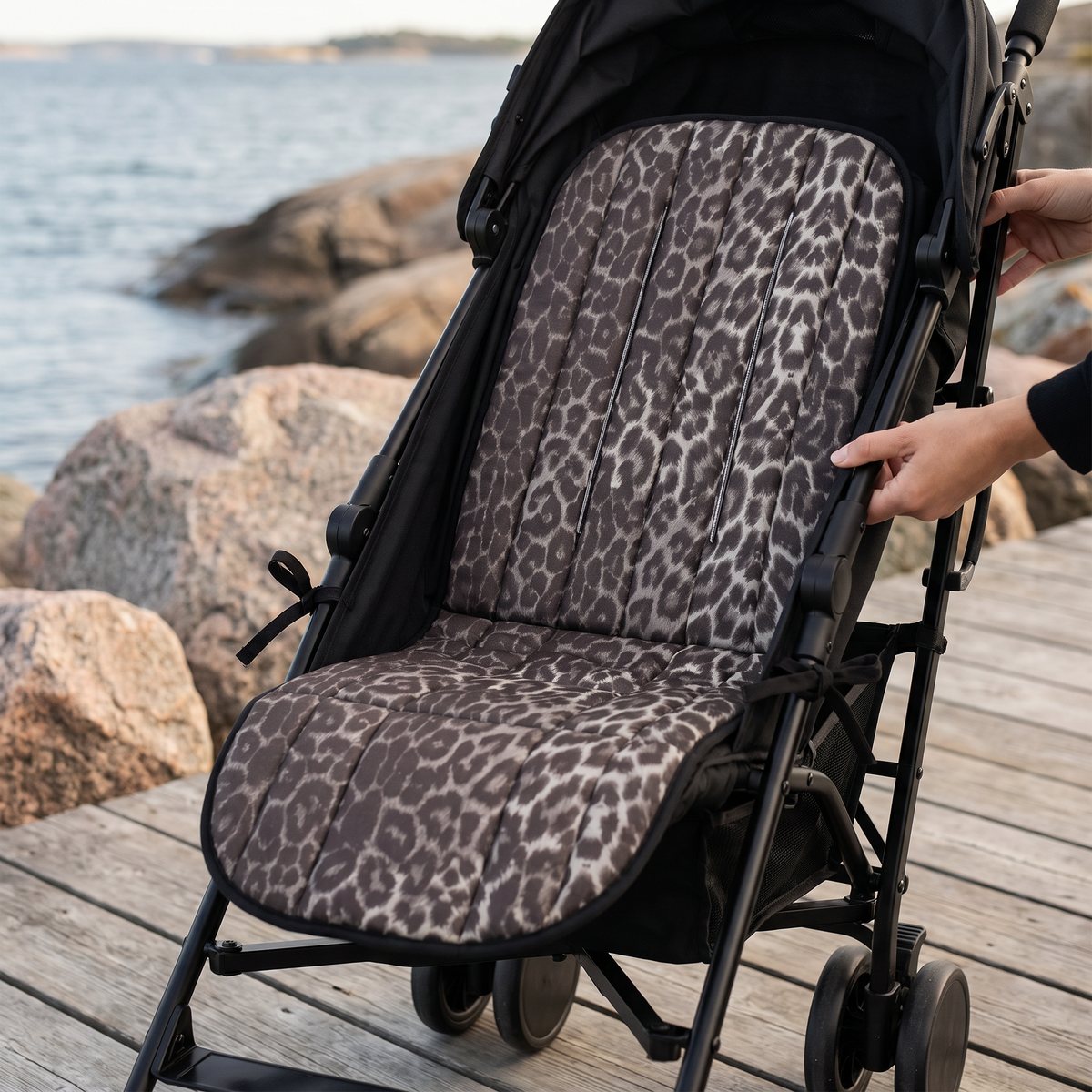 Leopardmönstrad sittdyna fastknuten i en svart sulky på en träbrygga vid granithällar i skärgården.