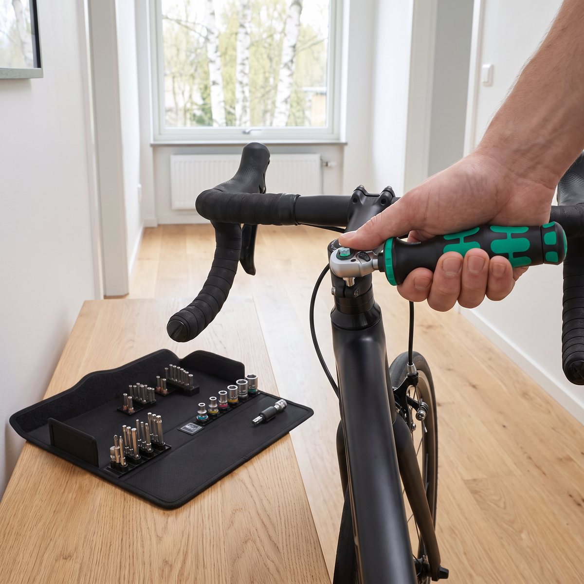 Wera Click-Torque A 6 momentnyckel drar en bult i styrstammen på en racercykel i en ljus hall, med det öppna fodralet med hylsor och bits på en bänk
