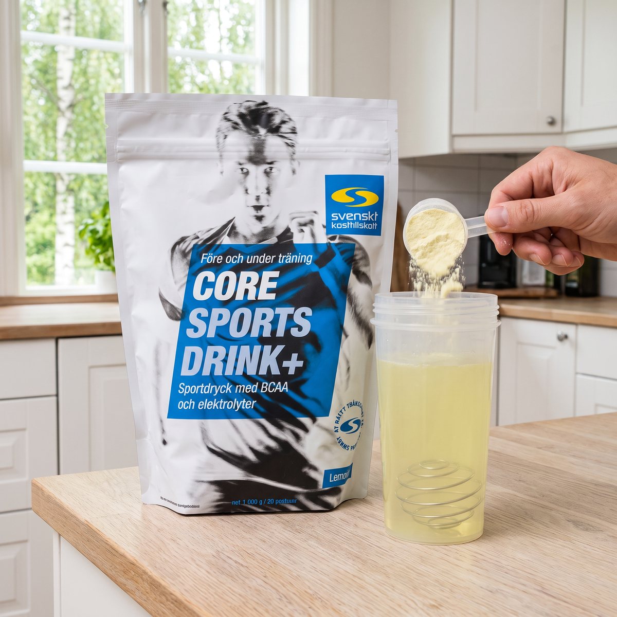 Core Sports Drink+ i silverfärgad påse på en köksbänk i ett svenskt hem, med pulver som hälls i en shaker