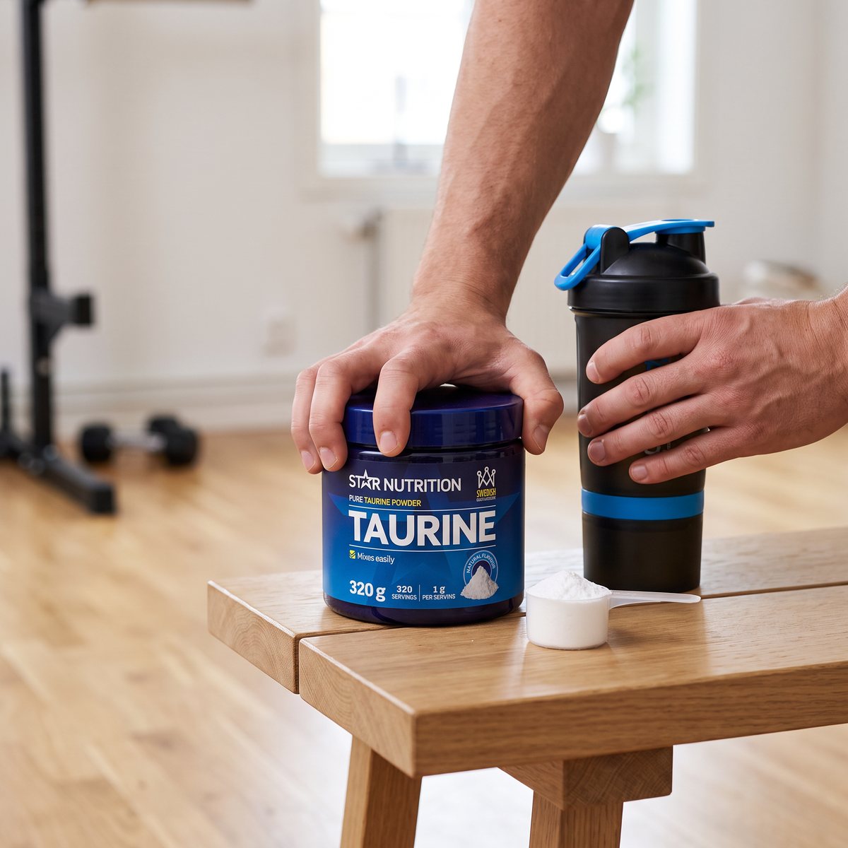 Hand på en burk Star Nutrition Taurine bredvid en shaker och en mätsked i ett svenskt hemmagym