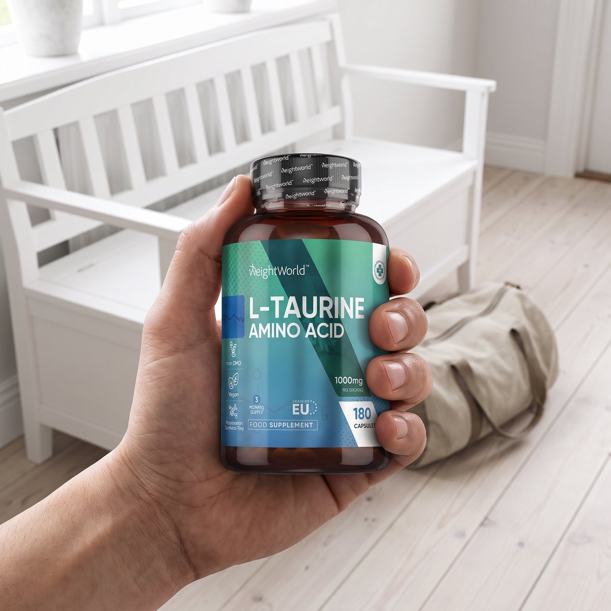 Hand som håller en burk WeightWorld L-Taurine i en svensk hall med vit bänk, trägolv och en träningsväska