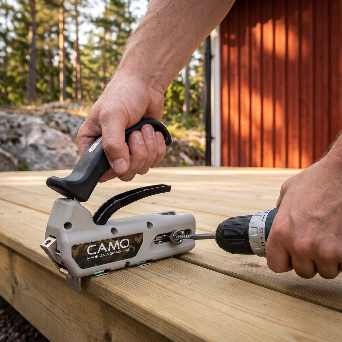 Camo Marksman Pro-NB tryckt mot kanten på en trallbräda på en altan vid ett rött svenskt trähus