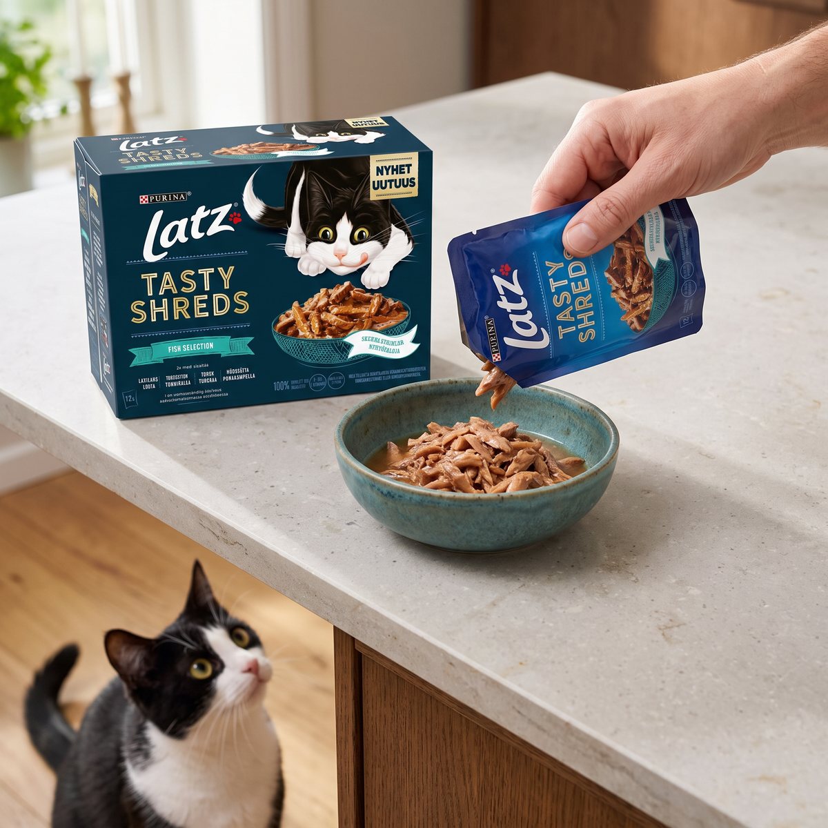 Kartong med Latz Tasty Shreds Fish Selection på en stenbänk i ett svenskt kök, en hand häller fiskstrimlor i en skål