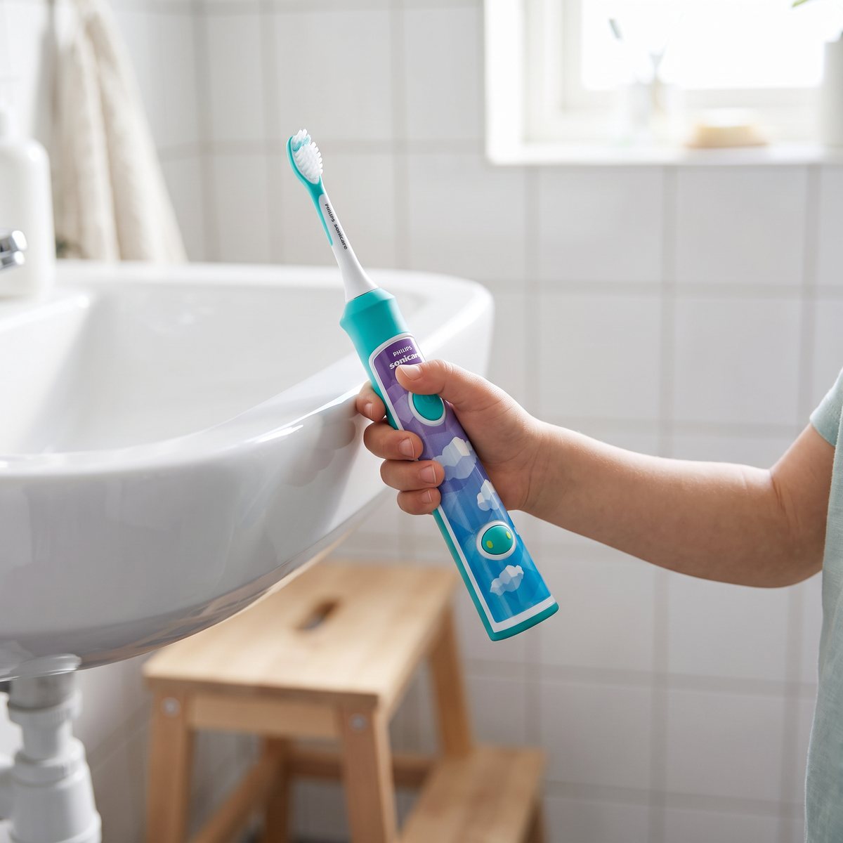 Barnhand håller Philips Sonicare For Kids vid ett handfat i ett svenskt badrum