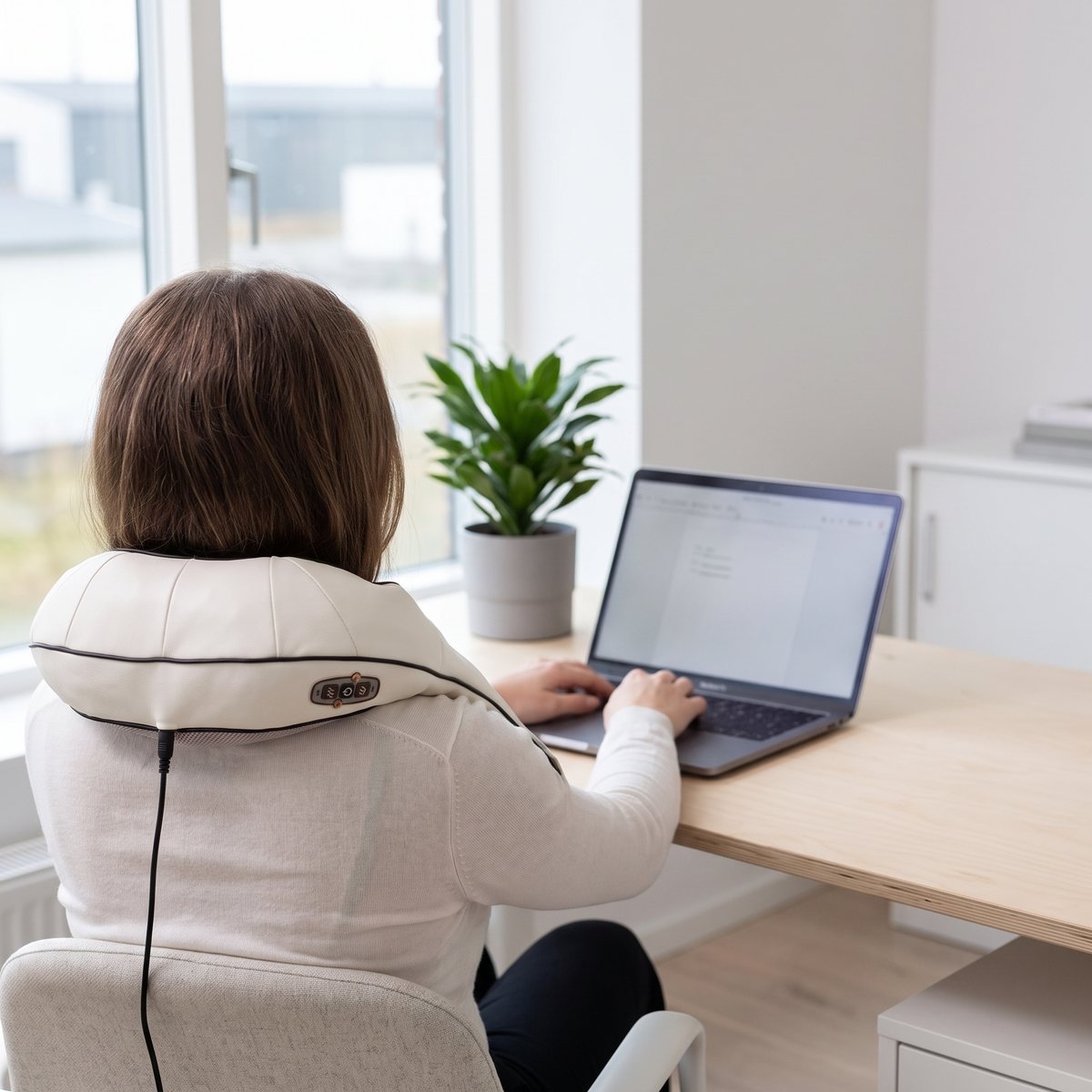 CWC Nackmassage i krämvitt runt nacke och axlar på en person som arbetar vid ett ljust skrivbord i ett svenskt kontor