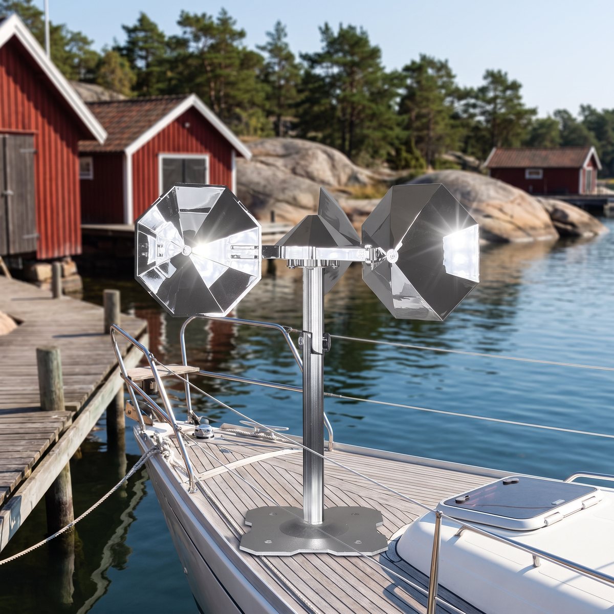 Blank vindsnurra med två speglande koppar på ett aluminiumstativ på däcket av en segelbåt vid en brygga i skärgården