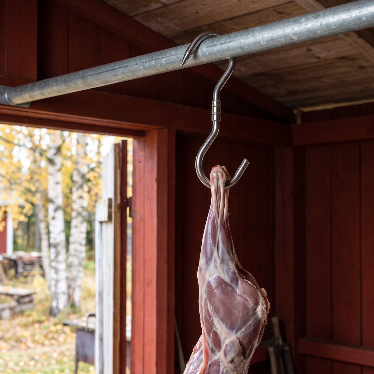 Eurohunt Ledad slaktkrok med rörlig länk som håller ett flått rådjurslår i ett rödmålat svenskt slakthus