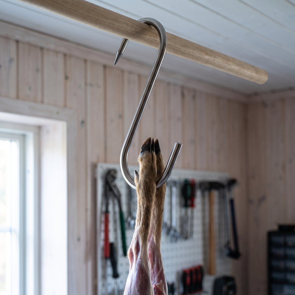 Eurohunt Slaktkrok S-Hook med ett rådjursben på en trästång i ett svenskt garage