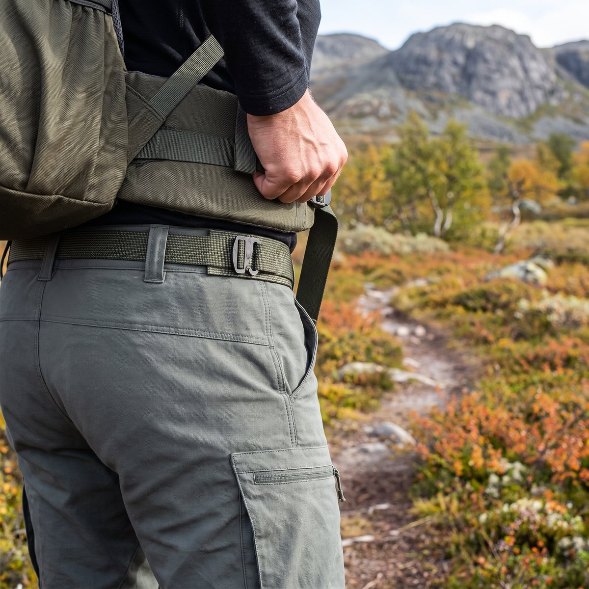 Savotta G-Hook Trousers Belt i grön polyester med platt G-krok under en ryggsäcks höftbälte på en fjällstig i höstfärger
